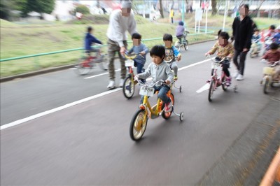 交通公園の補助輪付き自転車に乗る幼児